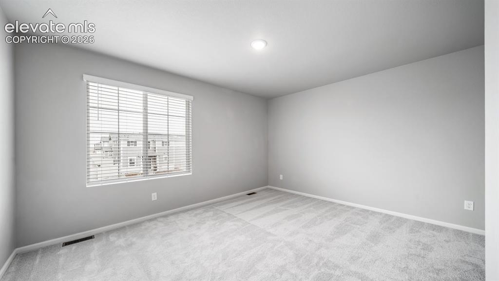 Image 28 of 34: Spacious room featuring light gray walls, plush gray carpeting, and white b