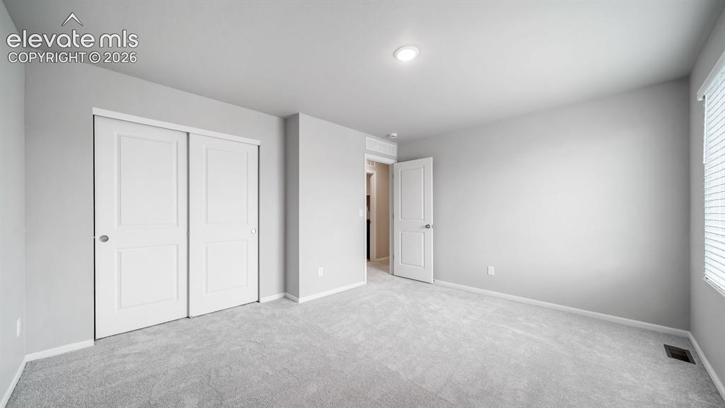Image 29 of 34: Bedroom featuring light gray walls, gray carpet, a white two-panel sliding