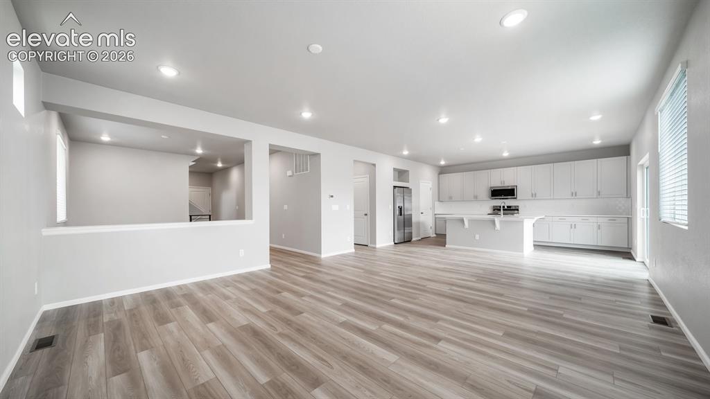 Image 9 of 34: Open-concept living area featuring wood-finish flooring, recessed lighting,