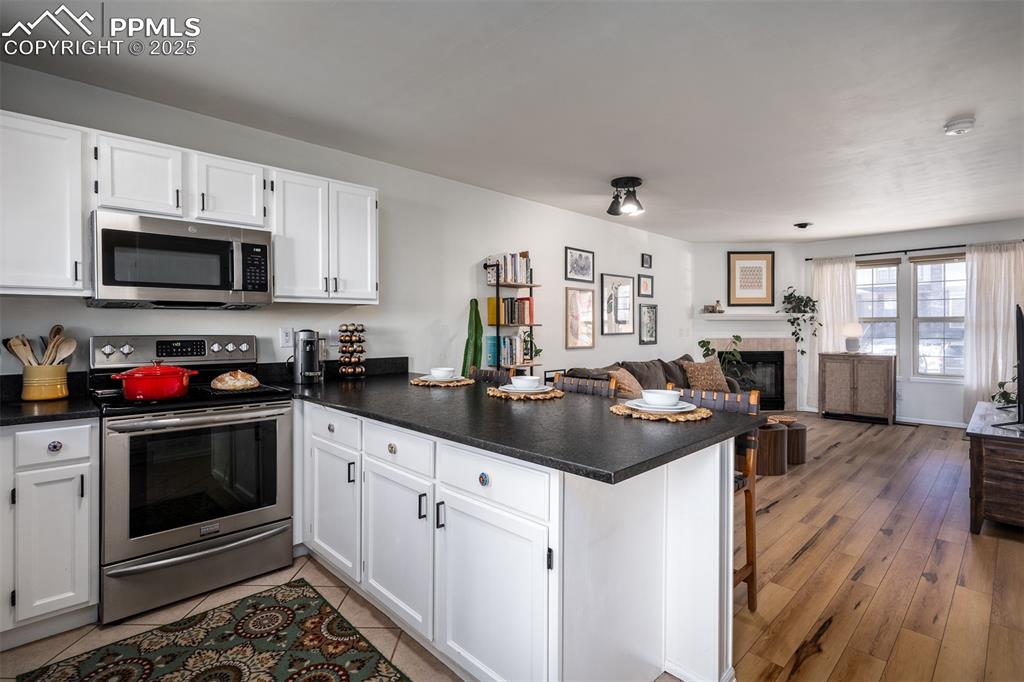 Image 14 of 47: Kitchen with a peninsula, white cabinets, open floor plan, appliances with