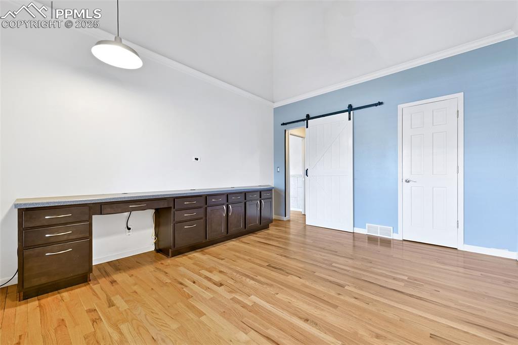 Image 10 of 25: Unfurnished office featuring a towering ceiling, light wood finished floors