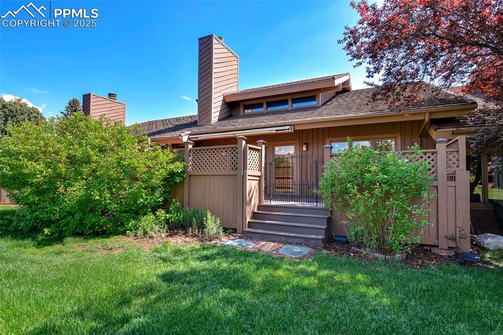 Image 12 of 25: Rear view of property featuring a chimney and a lawn