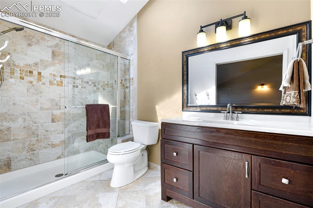 Image 15 of 25: Full bath with toilet, vanity, a shower stall, and tile patterned flooring