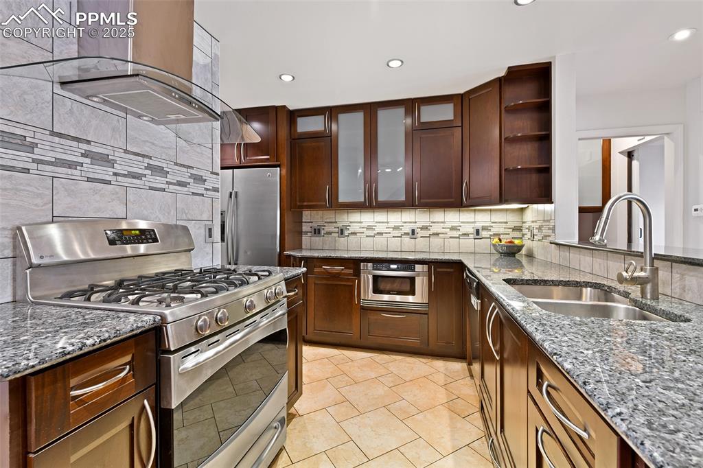 Image 7 of 25: Kitchen with appliances with stainless steel finishes, a sink, island exhau