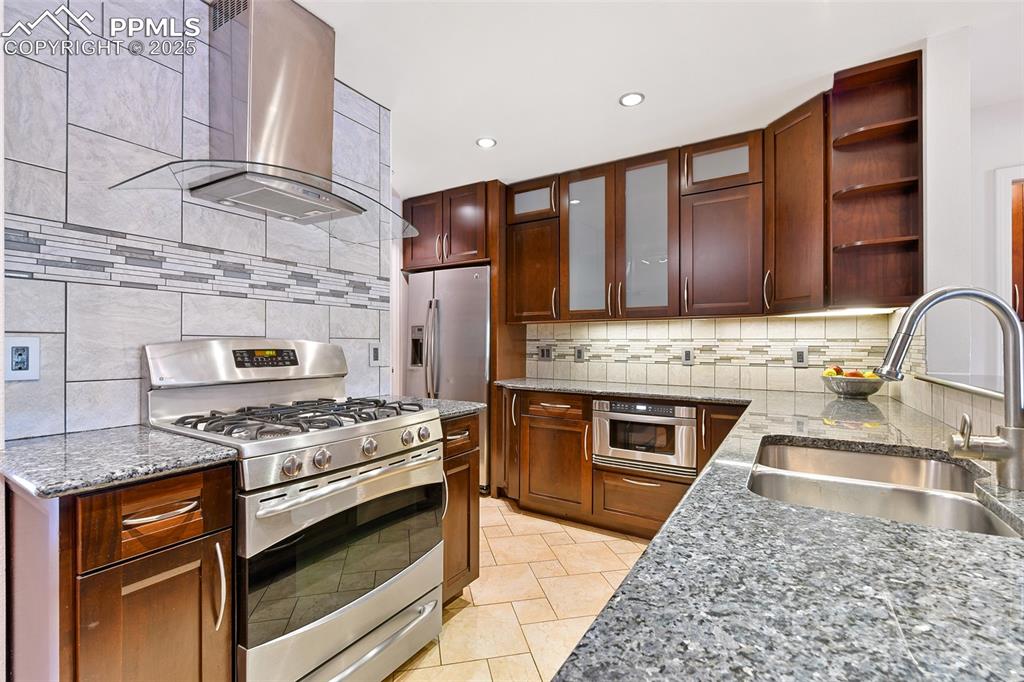 Image 8 of 25: Kitchen featuring stainless steel appliances, a sink, wall chimney range ho