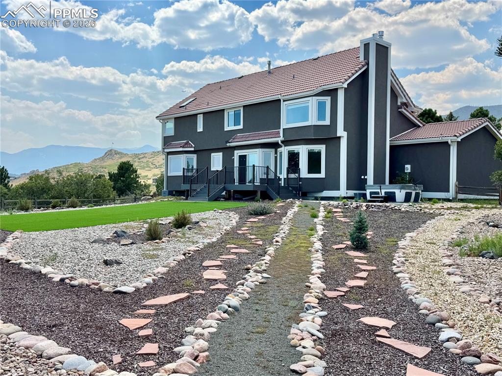 Image 2 of 48: Back of house featuring a chimney, a mountain view, a tile roof, stucco sid