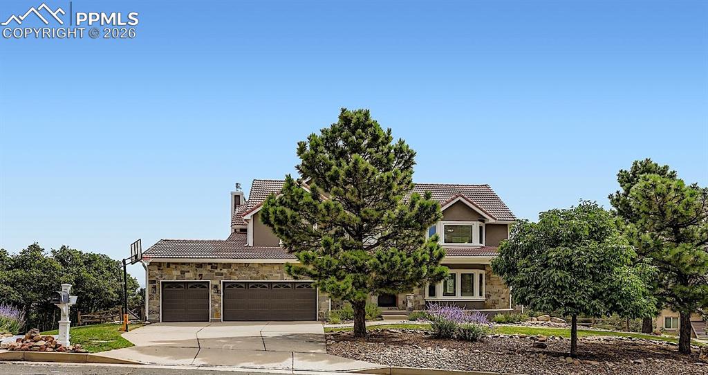 Image 3 of 48: Obstructed view of property featuring a tiled roof, stone siding, driveway,