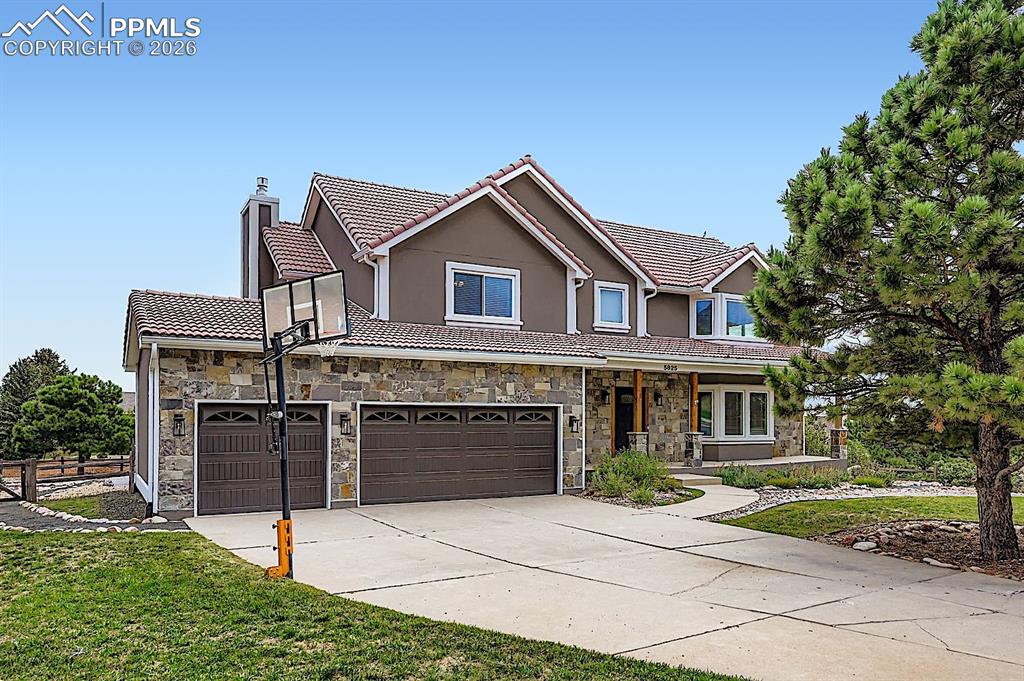 Image 4 of 48: View of front of house featuring a chimney, driveway, a tiled roof, stucco 