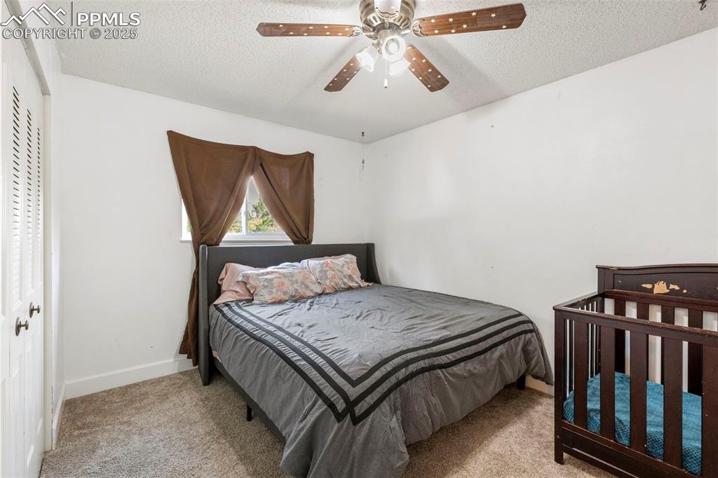 Image 12 of 32: Bedroom with light colored carpet, a textured ceiling, a ceiling fan, and a
