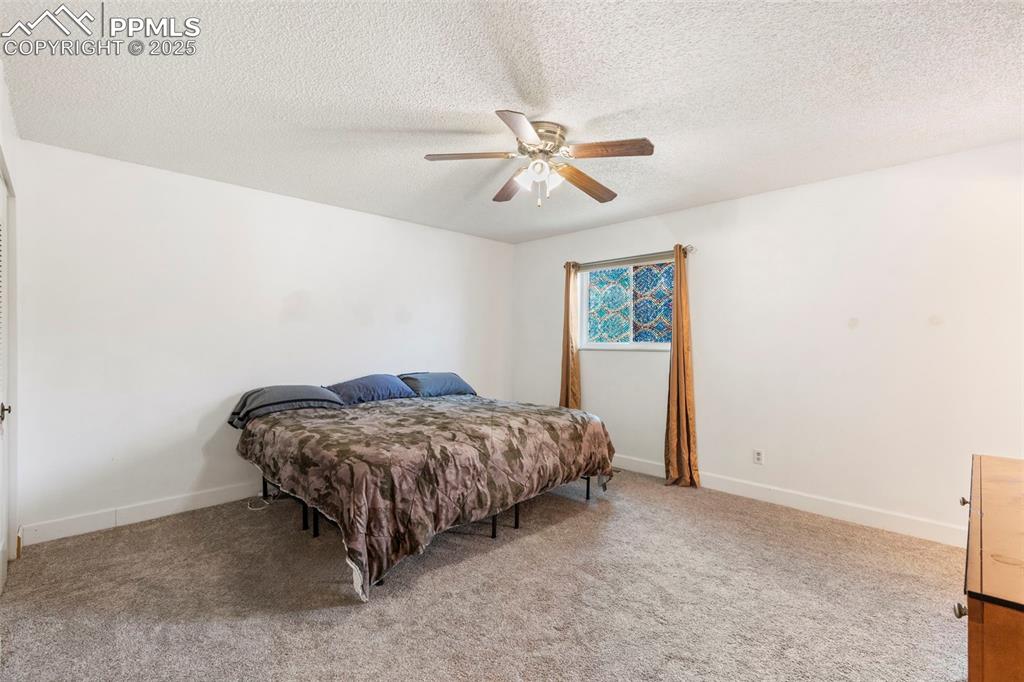 Image 13 of 32: Bedroom featuring light colored carpet, a ceiling fan, and a textured ceili