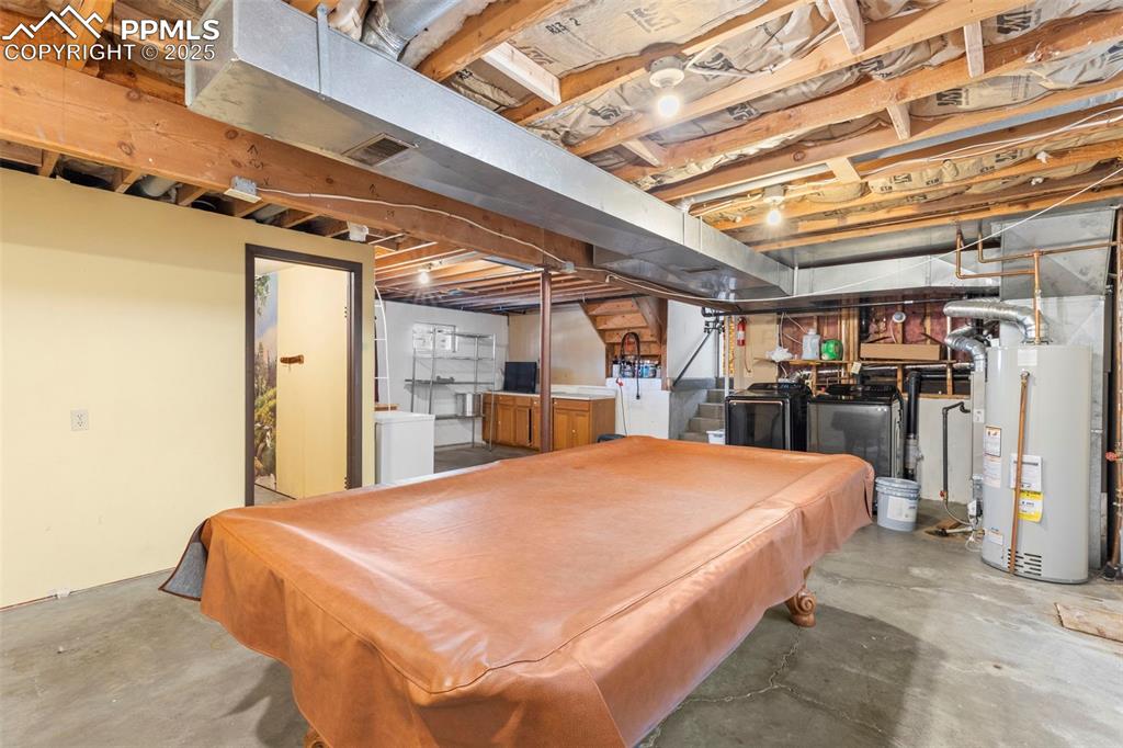 Image 20 of 32: Playroom featuring unfinished concrete flooring, pool table, water heater, 