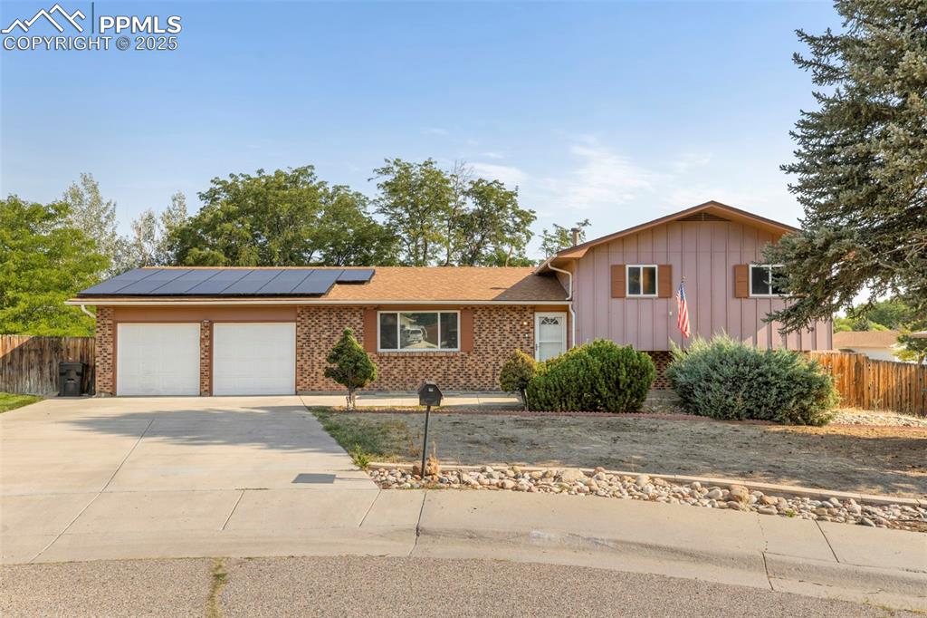 Image 26 of 32: View of front of property featuring roof mounted solar panels, driveway, a 
