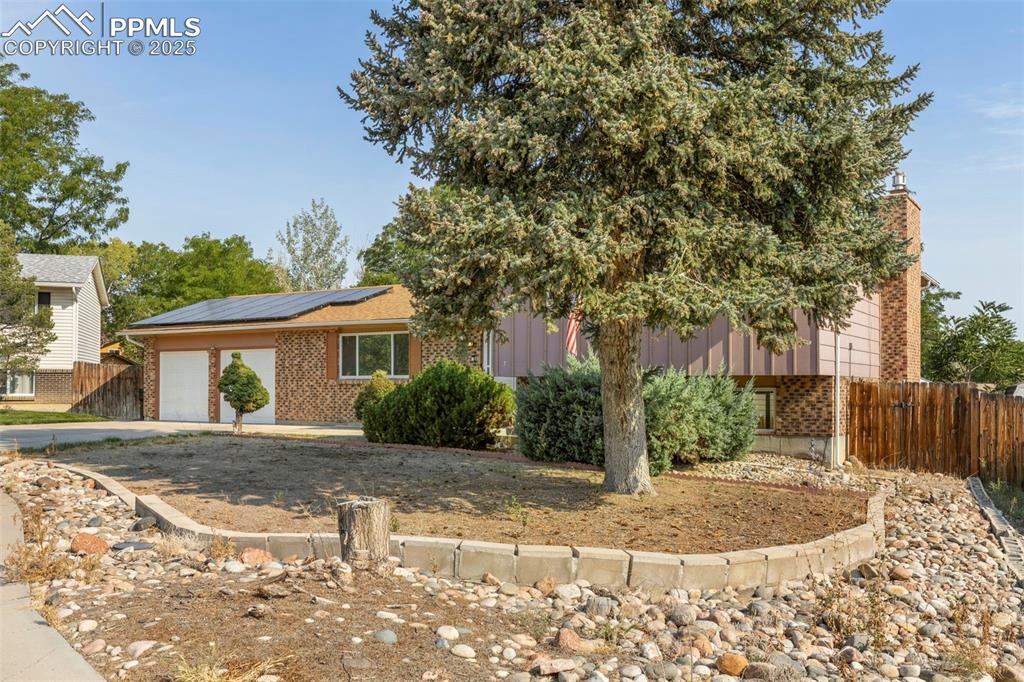 Image 27 of 32: View of front facade with solar panels, brick siding, a garage, and concret