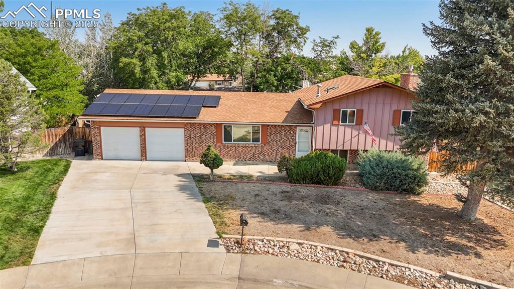 Image 28 of 32: Split level home featuring solar panels, brick siding, driveway, an attache
