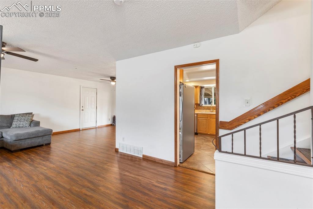 Image 3 of 32: Unfurnished living room featuring a textured ceiling, dark wood-type floori