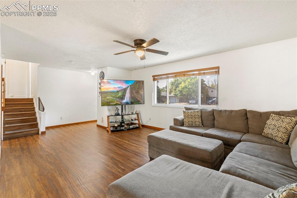Image 5 of 32: Living area featuring stairs, wood finished floors, a textured ceiling, and