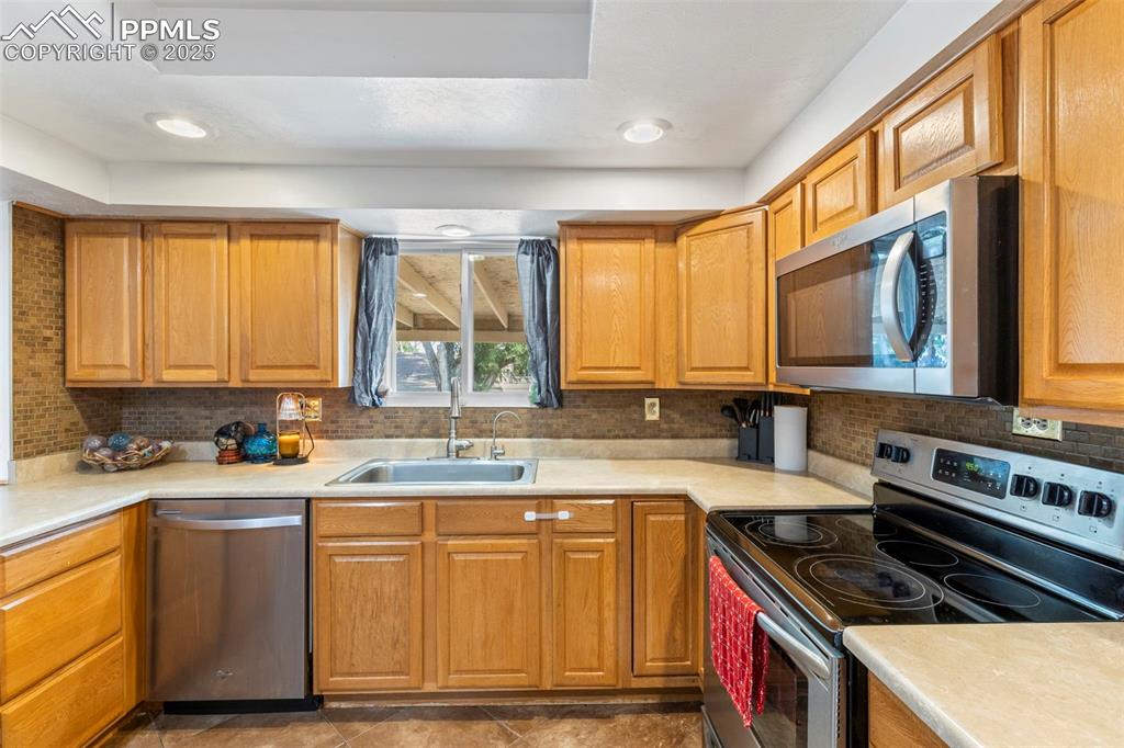 Image 9 of 32: Kitchen with appliances with stainless steel finishes, decorative backsplas