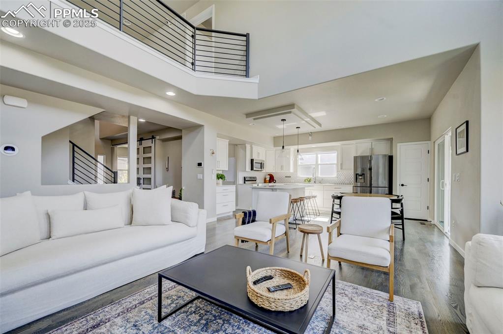 Image 10 of 50: Living area with light wood-style flooring, recessed lighting, a towering c
