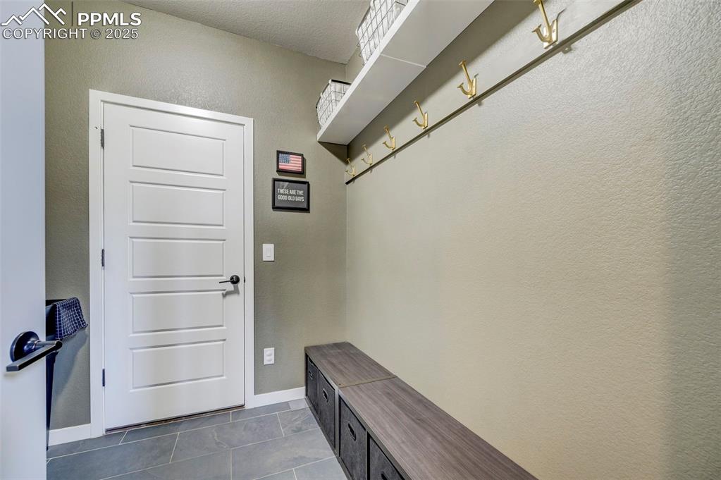 Image 11 of 50: Mudroom with a textured wall and dark tile patterned floors