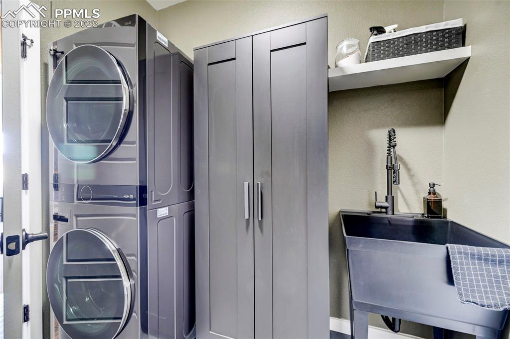 Image 12 of 50: Washroom with stacked washer / drying machine and a textured wall