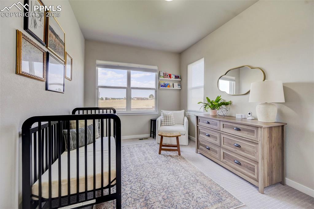 Image 13 of 50: Bedroom featuring light colored carpet and a nursery area