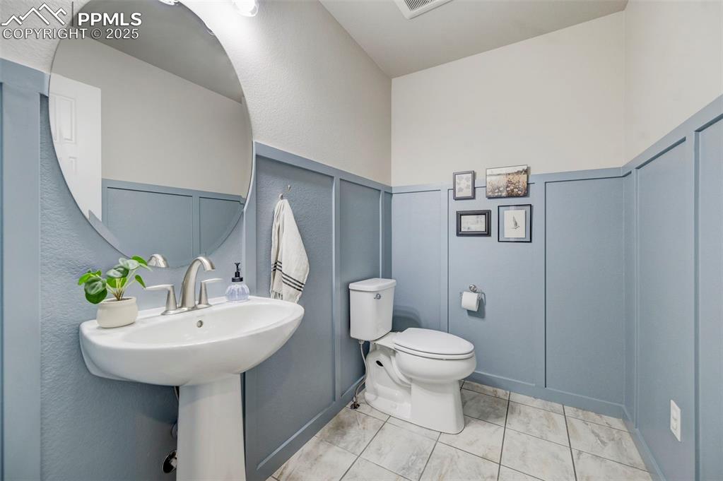 Image 15 of 50: Half bathroom featuring a decorative wall, light tile patterned flooring, a