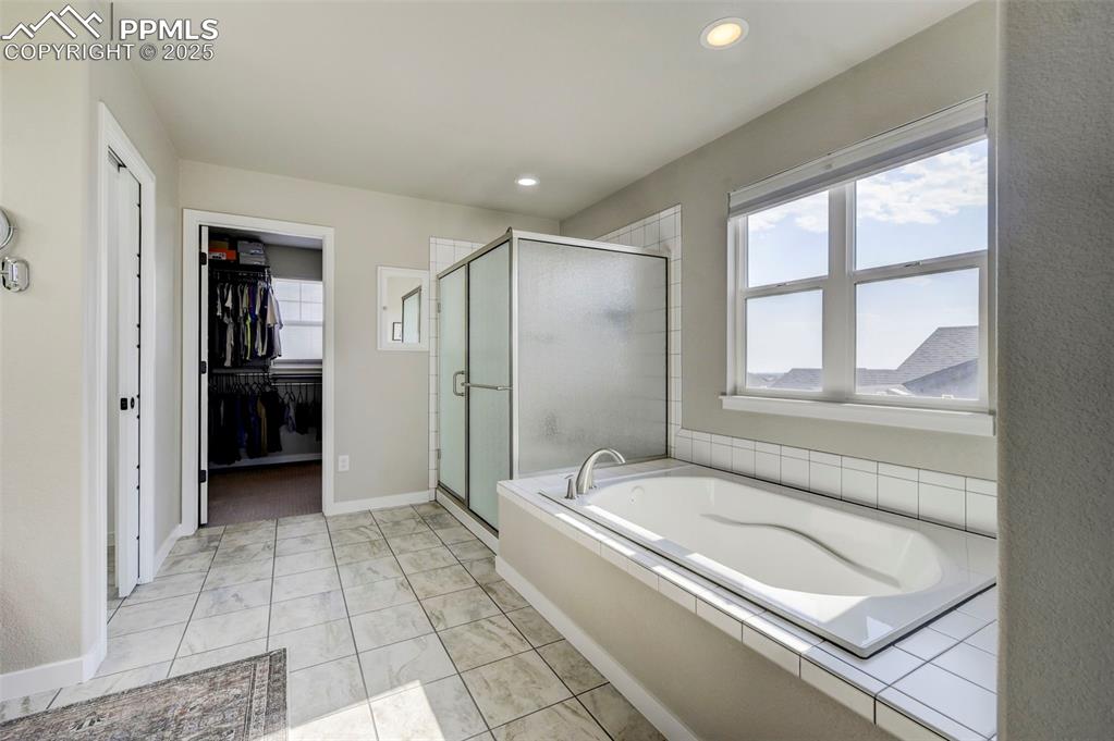 Image 19 of 50: Bathroom with a garden tub, a shower stall, healthy amount of natural light