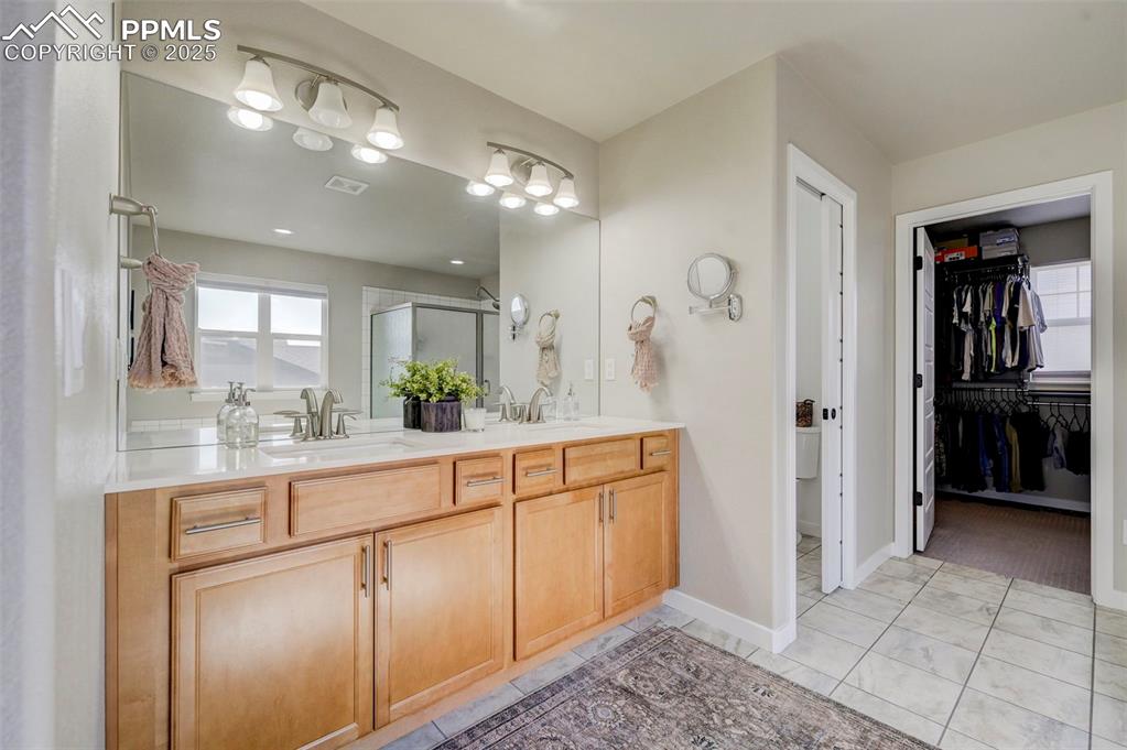Image 20 of 50: Full bathroom featuring double vanity, a stall shower, a walk in closet, an