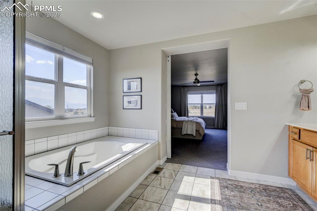 Image 22 of 50: Full bathroom featuring vanity, a bath, ensuite bathroom, ceiling fan, and