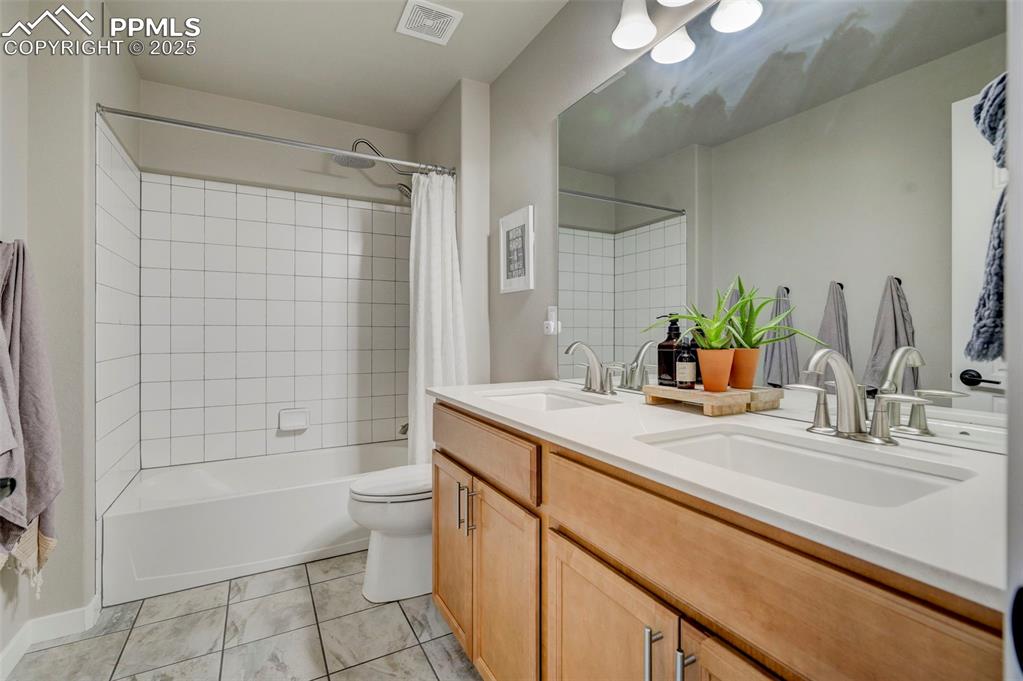 Image 25 of 50: Full bathroom featuring shower / tub combo, double vanity, and light tile p