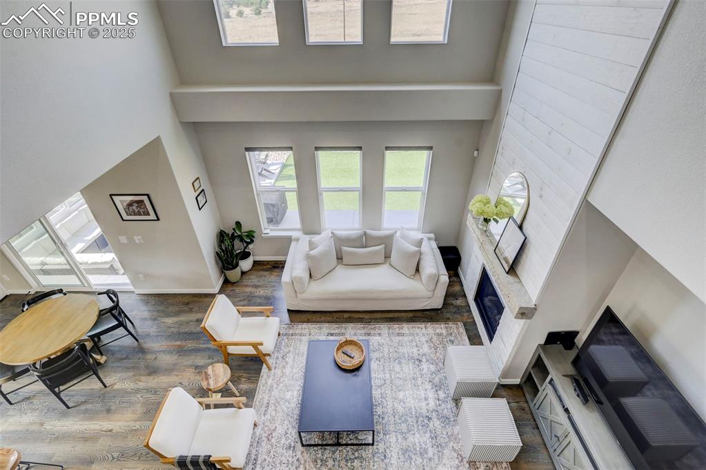 Image 30 of 50: Living room featuring a towering ceiling, a fireplace, and wood finished fl