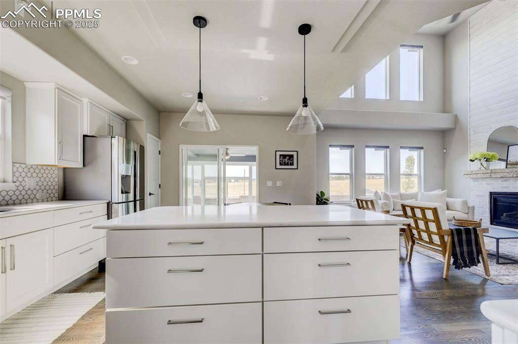 Image 37 of 50: Kitchen featuring white cabinetry, hanging light fixtures, backsplash, dark