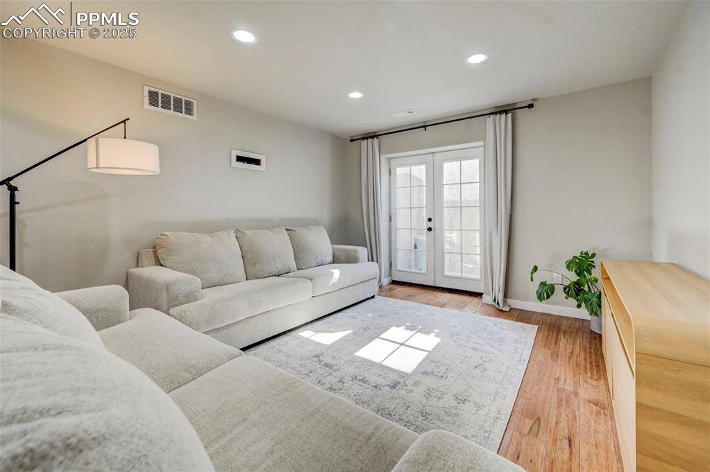 Image 41 of 50: Living area with wood finished floors, french doors, and recessed lighting