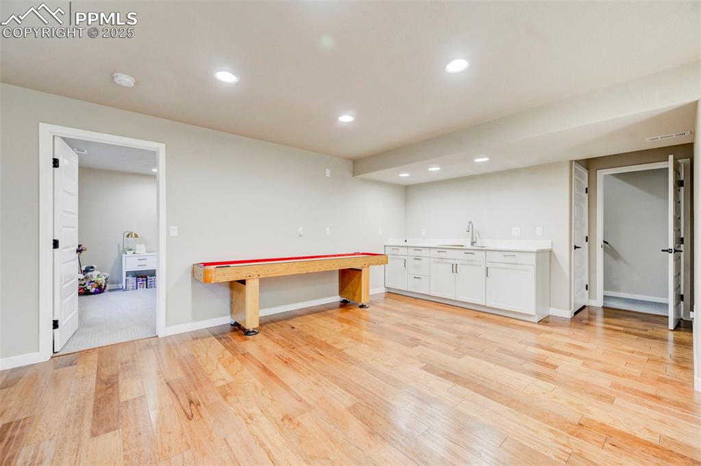 Image 42 of 50: Kitchen with white cabinets, recessed lighting, and light wood finished flo