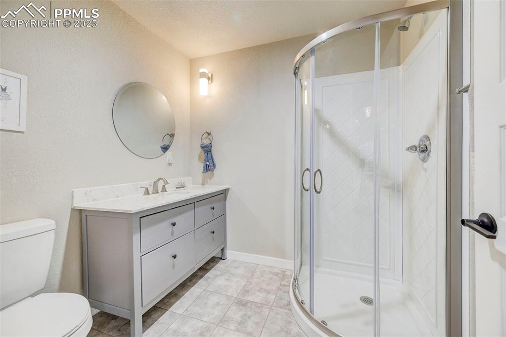 Image 45 of 50: Full bathroom featuring vanity, a stall shower, light tile patterned floori