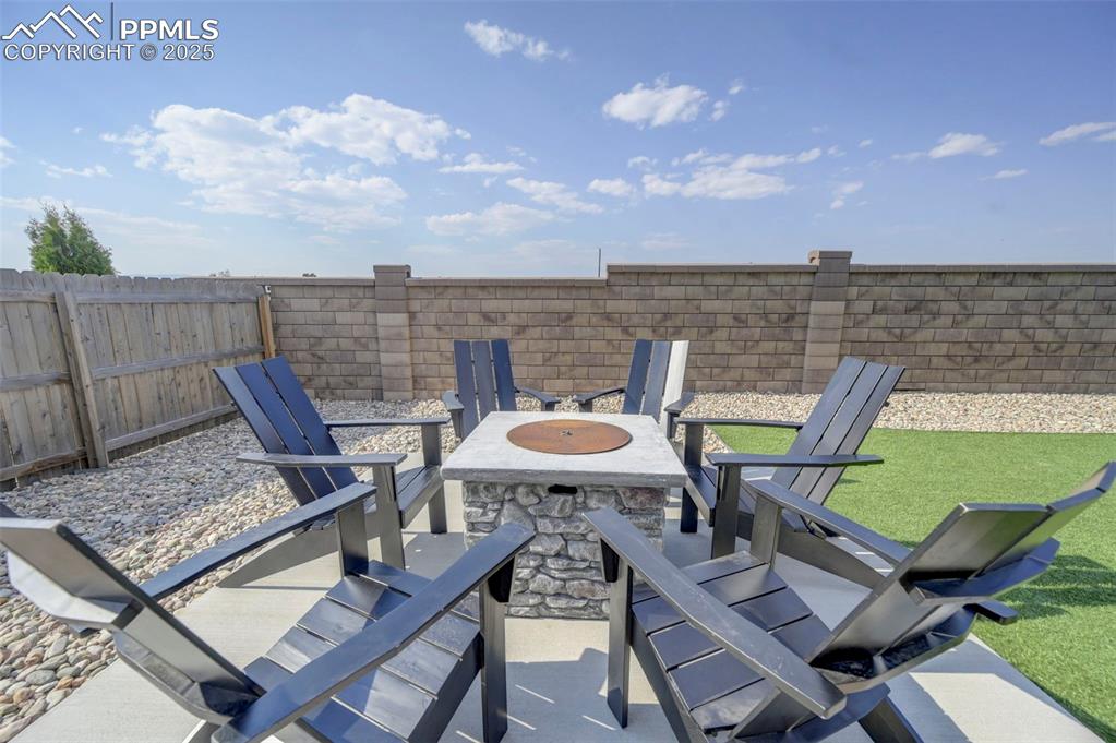 Image 47 of 50: Fenced backyard with a patio and a fire pit