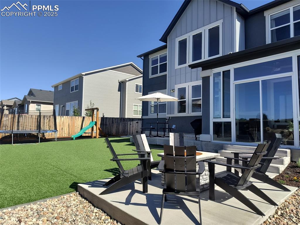 Image 49 of 50: Fenced backyard featuring a trampoline, a playground, a residential view, a