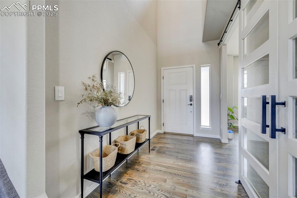 Image 6 of 50: Entrance foyer featuring wood finished floors, a barn door, and a high ceil