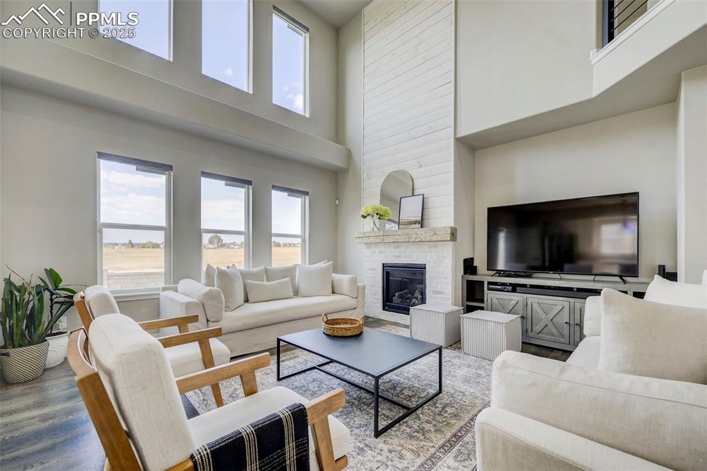 Image 8 of 50: Living room featuring a towering ceiling, a large fireplace, and wood finis