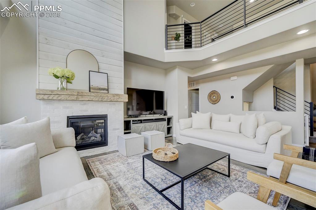 Image 9 of 50: Living room with a towering ceiling, a fireplace, recessed lighting, and st