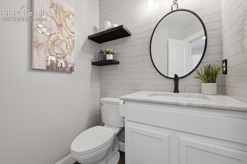 Image 22 of 50: Charming main level bath with tile wall and open shelving!
