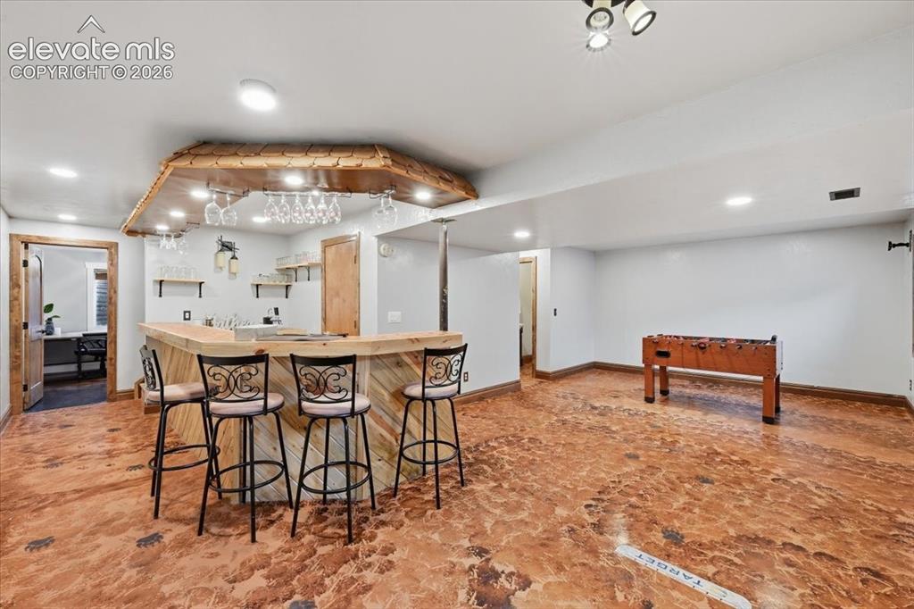 Image 32 of 50: Wonderful basement with fun wet bar and stained concrete flooring!