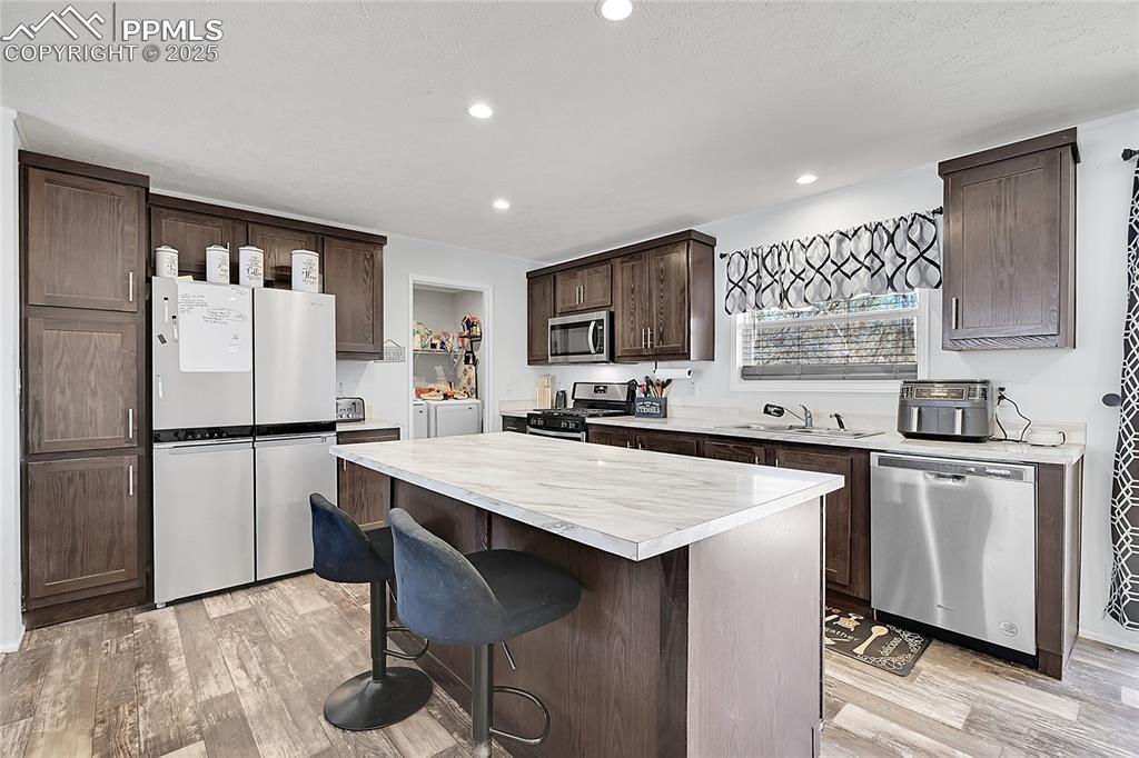 Image 3 of 12: Kitchen featuring a sink, appliances with stainless steel finishes, dark br