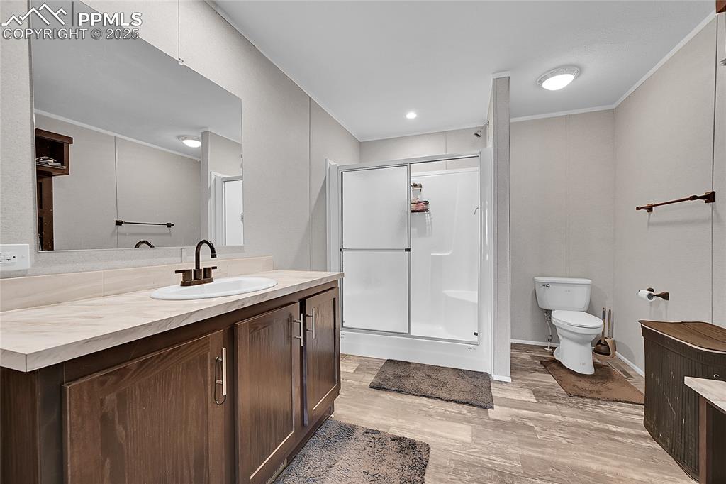 Image 7 of 12: Full bathroom featuring vanity, a stall shower, toilet, and wood finished f