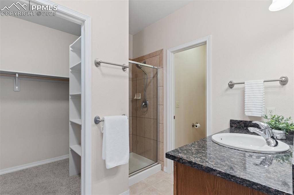 Image 18 of 27: Full bathroom featuring a spacious closet, a stall shower, and vanity