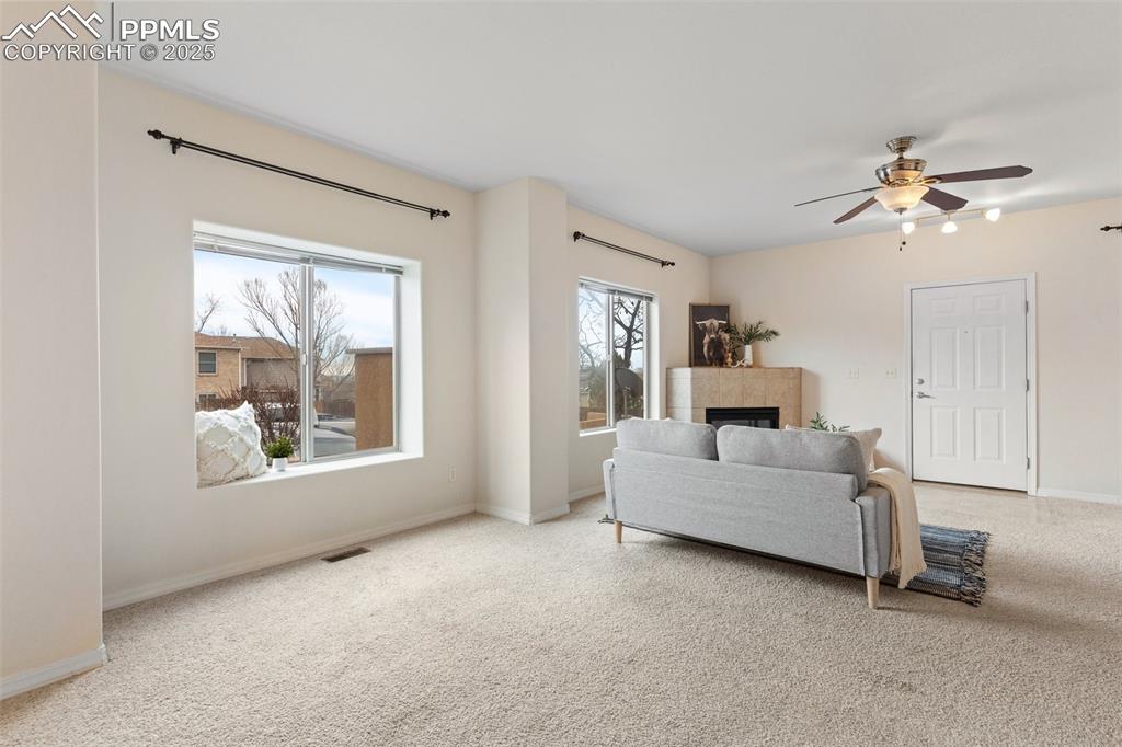 Image 6 of 27: Living area with carpet floors, a fireplace, and ceiling fan