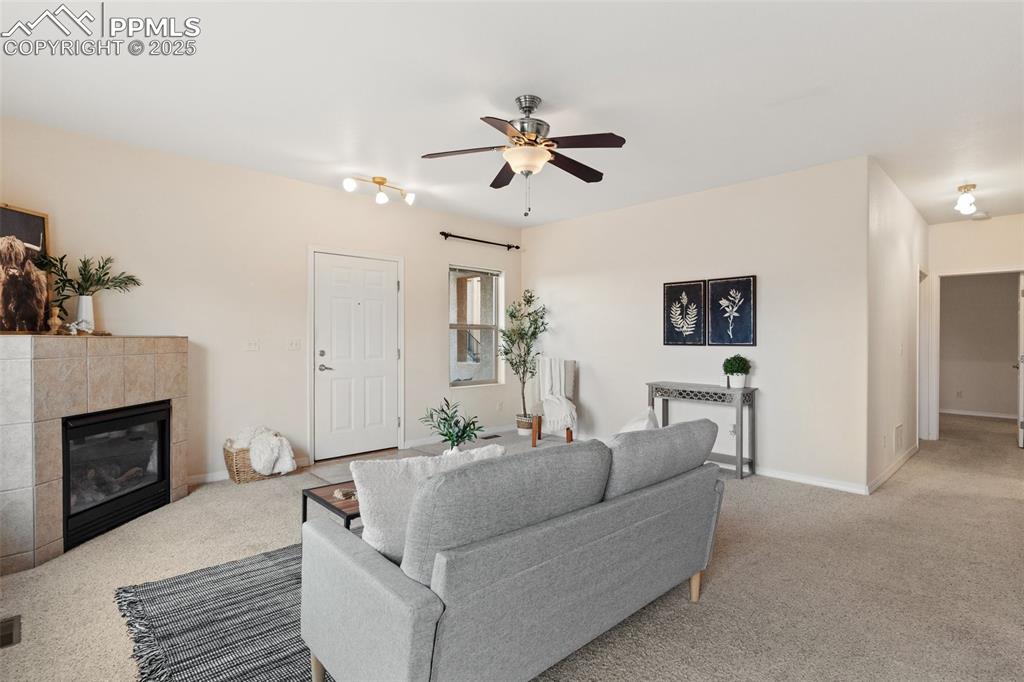 Image 7 of 27: Carpeted living area with a tiled fireplace and ceiling fan