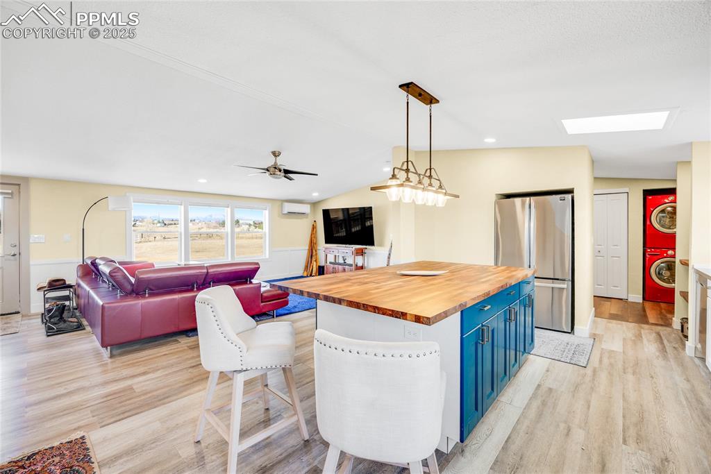 Image 11 of 49: Kitchen featuring blue cabinetry, wooden counters, freestanding refrigerato