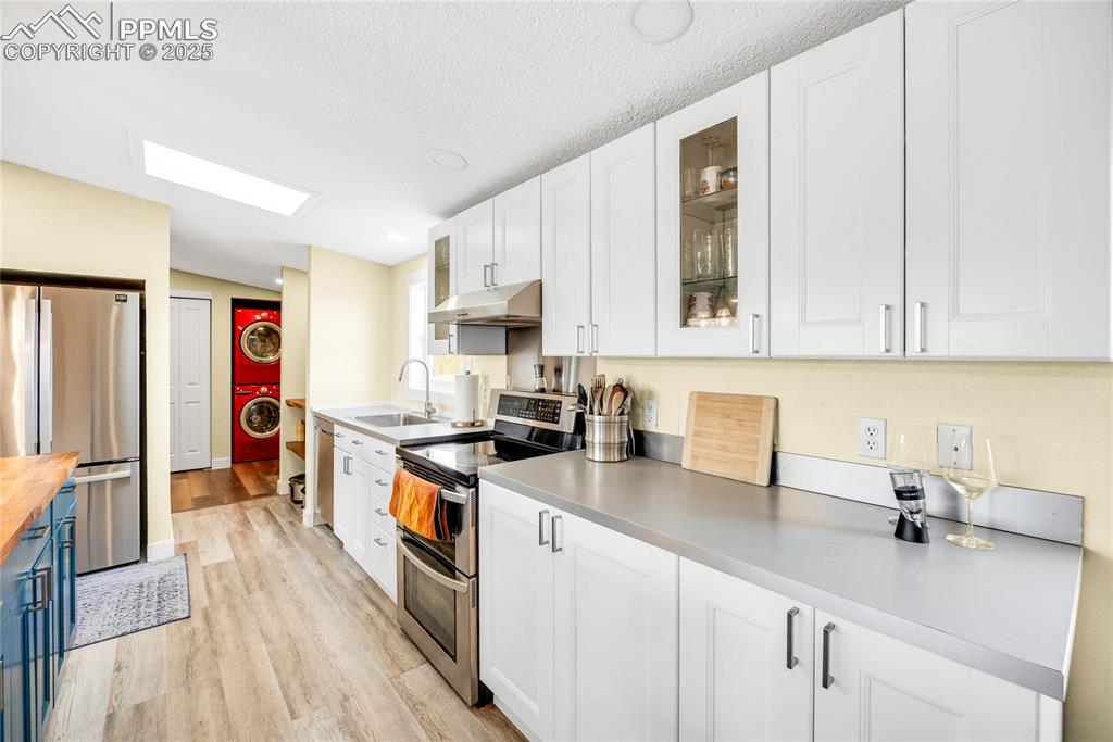 Image 12 of 49: Kitchen featuring appliances with stainless steel finishes, white cabinets,