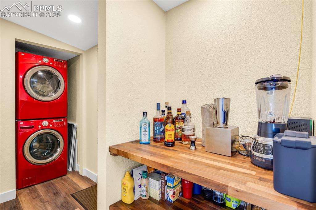Image 15 of 49: Laundry area featuring a textured wall, estacked washer and dryer, and dark